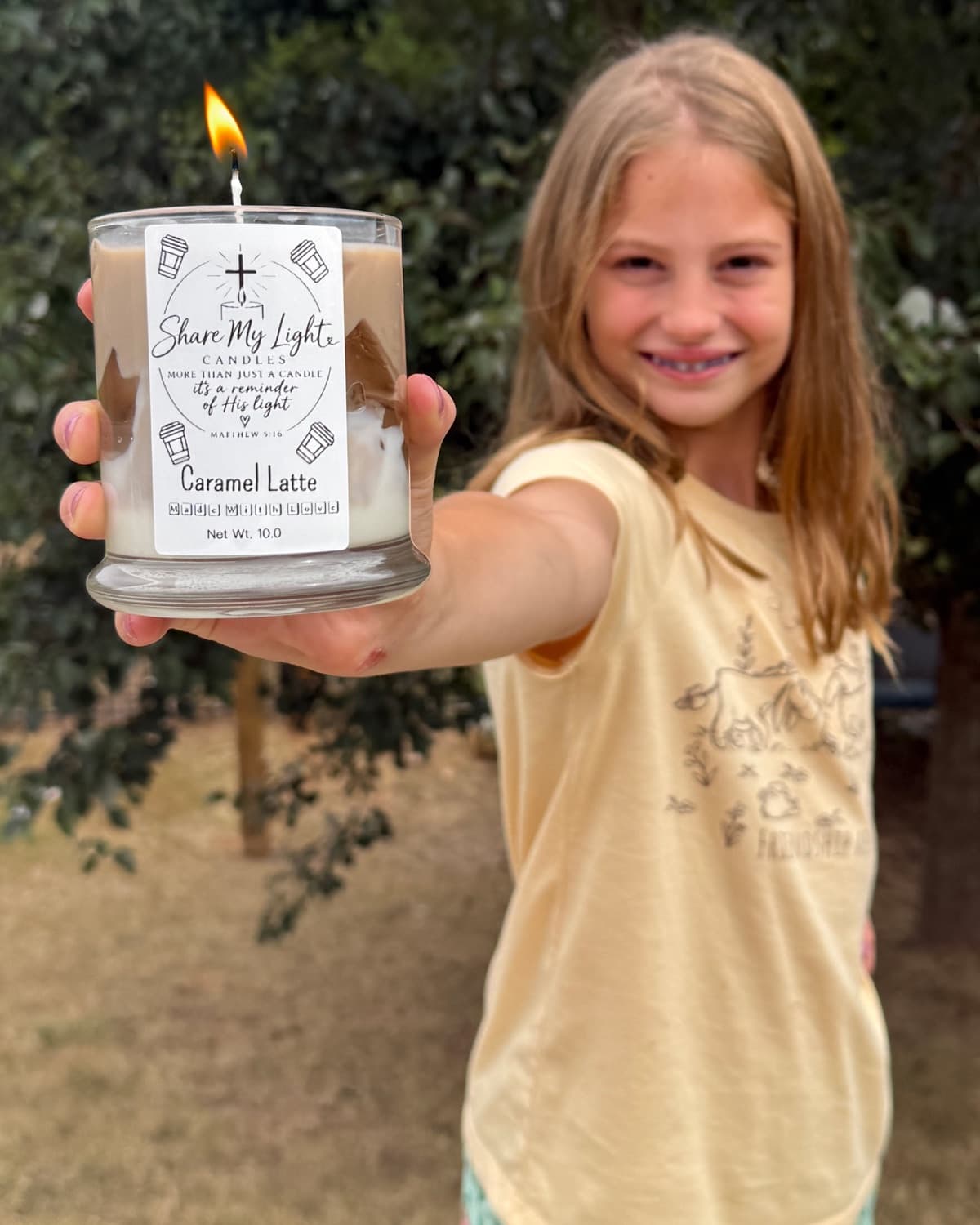 Penelope holding up a lit Caramel Latte candle
